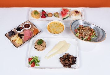 Image of dessert plate, salad, garnish, lentil soup, and meat tanderned dish in isolated environment in white-orange background.