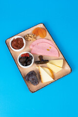 In the isolated environment in the blue background, the palli, olive, palm, ham, dried apricots, walm, wrap, cheddar cheese, the image of the garnish dish with Cheddar cheese .