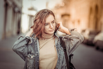 Stylish attractive woman in denim jacket on urban street