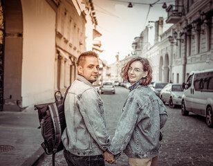 Fototapeta na wymiar Charismatic modern couple of tourists in love in denim jackets stroll along the urban street
