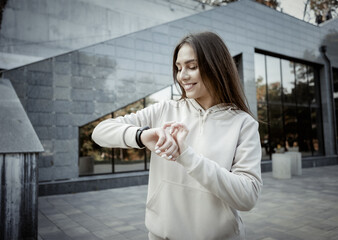 Fit runner woman in sportswear looks at smart bracelet measuring the pulse outdoor