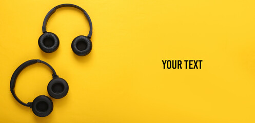 Two pairs of black wireless stereo headphones on yellow background. Top view. Space for your text