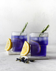 Blue tea from clitoria flowers in transparent glasses on marble stands