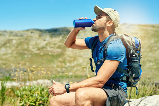 Its important to stay hydrated when hiking. Cropped shot of a young man taking a break while out on a hike.