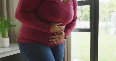 Video of midsection of plus size african american woman having stomach ache