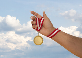 Man raising hand and holding gold medal. Concept of ambition perseverance and victory.