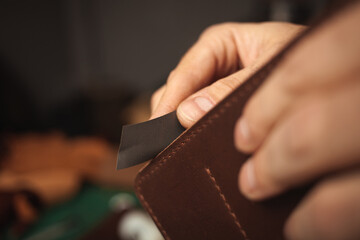 tanner makes genuine leather wallet, professional craftsman, closeup, indoor, authentic, business. Handiwork. sandpaper