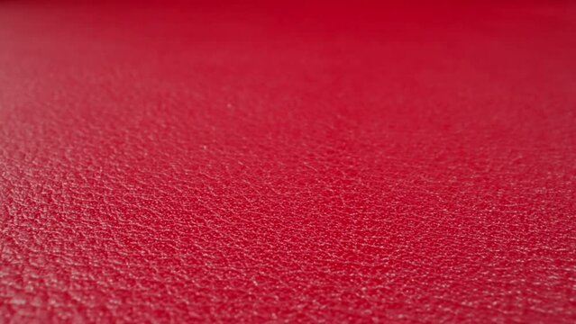 Texture of cow leather surface colored bright red as background extreme close view. Natural material for sewing different items. Abstract wallpaper