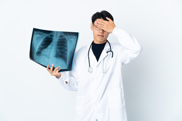 Young Chinese doctor man holding radiography isolated on white background covering eyes by hands. Do not want to see something