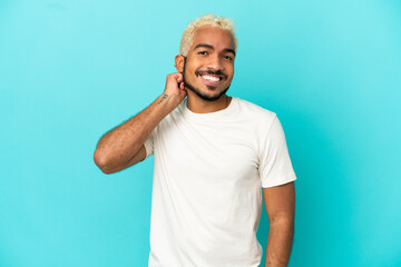 Young Colombian handsome man isolated on blue background laughing