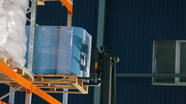 The forklift puts the goods on the shelves of the warehouse. warehouse work. Agrofibre put on the shelf of the warehouse