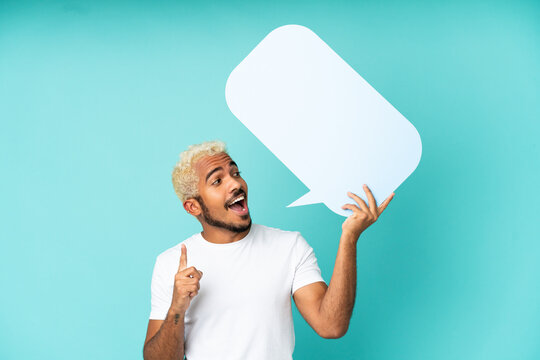 Young Colombian handsome man isolated on blue background holding an empty speech bubble and thinking