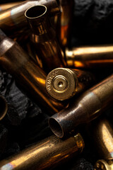 Empty shells from weapons on black smoldering coals. Consequences of the war. Dark back.