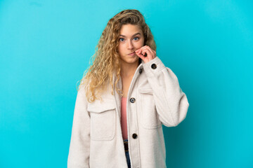 Young blonde woman isolated on blue background showing a sign of silence gesture