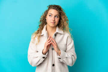 Young blonde woman isolated on blue background scheming something