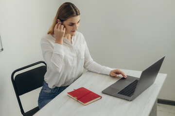 A young beautiful girl in headphones learns with internet chat, a Skype teacher prepares for an...