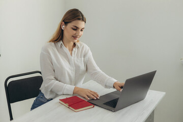A young beautiful girl in headphones learns with internet chat, a Skype teacher prepares for an...