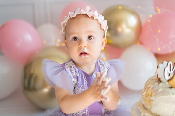 Cute little baby girl sitting on the floor and playing with his cake on his first birthday. Smash...