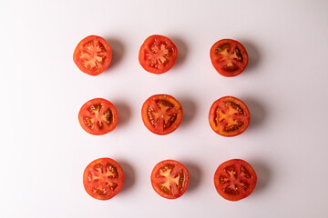 Overhead view of fresh tomato halves arranged in a row on white background