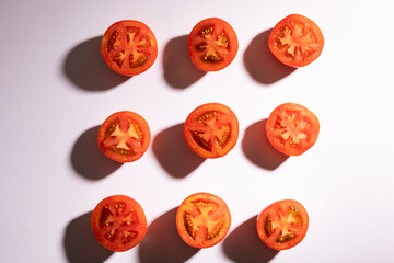 Directly above view of fresh red tomato halves arranged in a row on white background