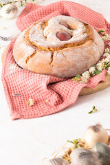 Portuguese traditional Easter cake with eggs. Typical Folar de Vale de Ilhavo, Aveiro, Portugal. Blossom flowers and colorful painted eggs decorated with feathers on easter table.