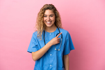 Young surgeon doctor woman isolated on pink background pointing to the side to present a product