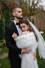 Young cheerful wedding couple. A bride with a veil, a charming groom in a black suit.