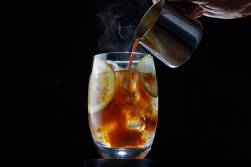 delicious alcoholic cocktail with hot coffee and ice on a dark background, close-up bartender pours coffee 