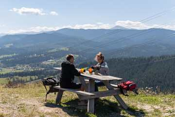 Fototapeta na wymiar A couple drinking tea and coffee at the wooden table in the mountains