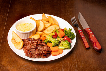 brazilian meal with succulent steak vegetables rustic potatoes and farofa angle view