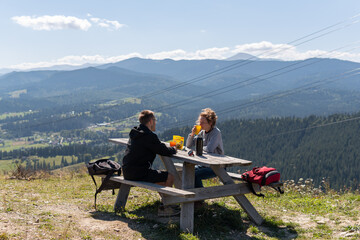 Fototapeta na wymiar A couple drinking tea and coffee at the wooden table in the mountains