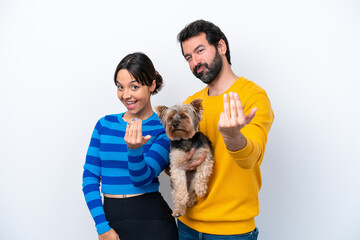 Obraz premium Young hispanic woman holding a dog isolated on white background inviting to come with hand