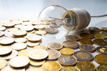 Light bulb, with coins around. Increase in electricity tariffs, energy dependence, energy sources...
