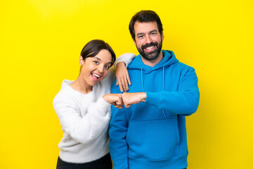 Young caucasian couple isolated on yellow background bumping fists