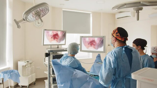 Laparoscopic surgeon looking at monitor during laparoscopic surgery. Process of gynecological surgery operation using laparoscopic equipment. Group of surgeons in operating room with surgery equipment