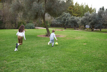 boy and girl playing football in a park