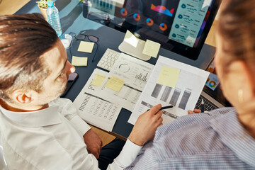 Business colleagues discussing financial data working together in office. People entrepreneurs working with charts and tables on computer. Two people working together