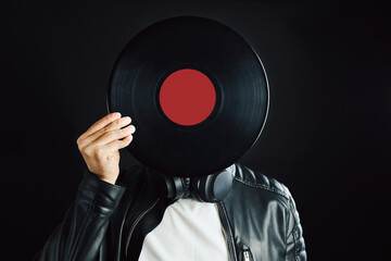 Man hiding behind retro vinyl record covering head. Rock style. Vintage music style. Male wearing...