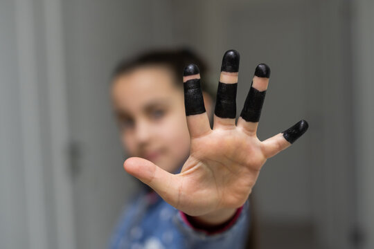 Cute little girl showing her black painted palm