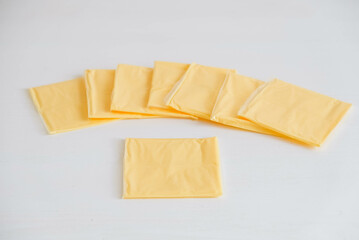 Separately packed cheese slices on a white wooden table background