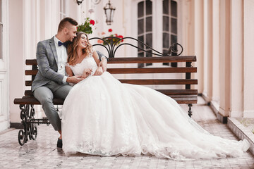 wedding day. beautiful bride in white long dress and young groom wearing in black suit are hugging...