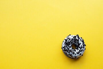 Donut with chocolate drops on a yellow background. Place for inscriptions.