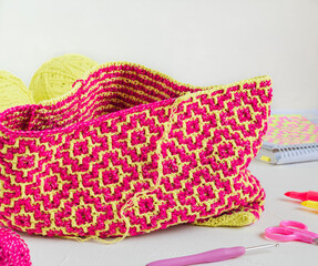 The process of creating a crochet bag with bright pink yellow rhombus. Modern crochet fabric with mosaic technique. Art handmade concept.