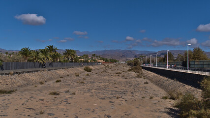 Fototapeta na wymiar View of empty canal in Meloneras the west of tourist resort Maspalomas, Gran Canaria, Spain on sunny day in winter season surrounded by palm trees.