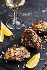 Fresh closed oysters with lemon on slate plate