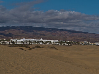 Beautiful landscape of nature reserve Dunas de Maspalomas in San Bartolome de Tirajana, southern Gran Canaria, Spain on sunny day with large hotel.