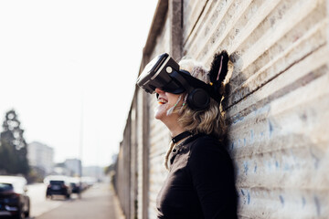 Nonconformist young woman laughing posing outdoor enjoying metaverse with 3D viewer