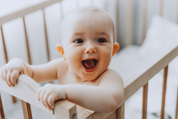 Candid shot of six month old infant baby  standing in the crib holding on to the side