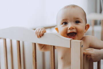 Candid shot of six month old infant baby  standing in the crib holding on to the side