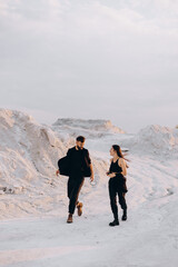Stylish couple walking and hugging walking on a background of white mountains. Lovely hipster couple enjoying time together. The concept of youth, love and lifestyle. Springtime.